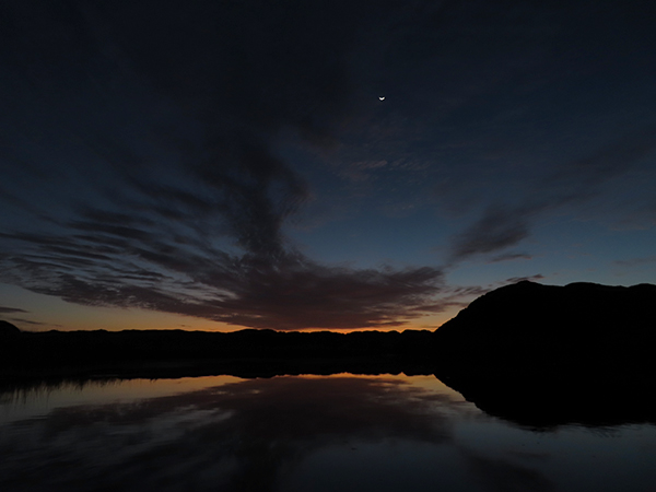 Waning moon rises above the desert sun